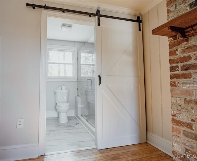 bathroom featuring hardwood / wood-style flooring, brick wall, toilet, and a shower with door