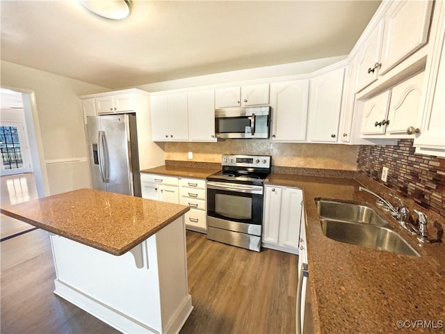 kitchen with a breakfast bar, sink, appliances with stainless steel finishes, white cabinets, and dark hardwood / wood-style floors