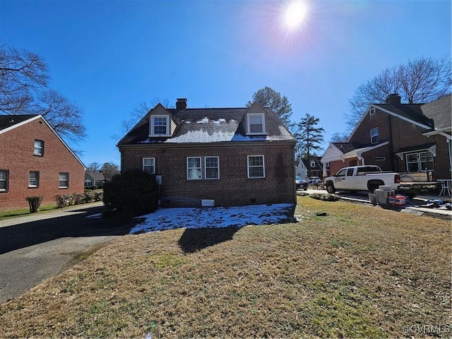 view of side of home with brick siding, a yard, a chimney, crawl space, and a residential view