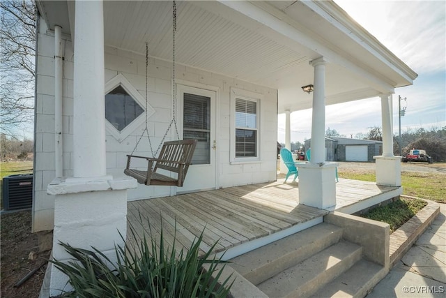 wooden terrace featuring covered porch, central AC unit, and a garage