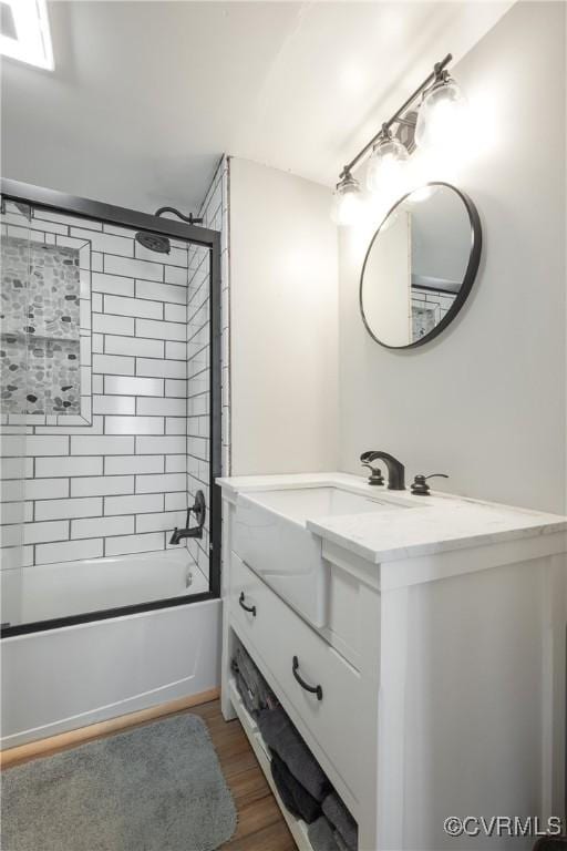 bathroom with tiled shower / bath combo, vanity, and wood-type flooring