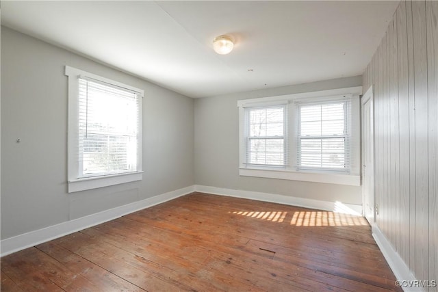 spare room featuring hardwood / wood-style floors, wooden walls, and a wealth of natural light