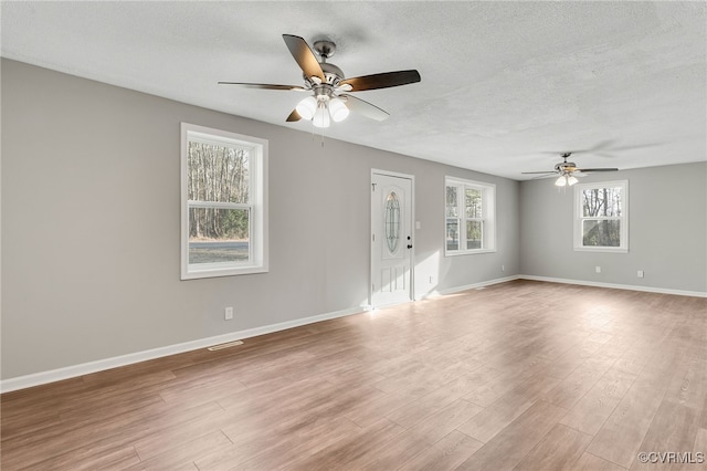 unfurnished room with light hardwood / wood-style flooring, ceiling fan, and a textured ceiling