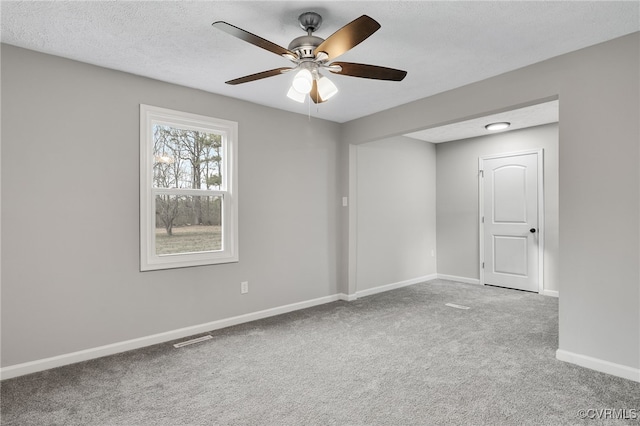 empty room featuring ceiling fan, a textured ceiling, and light colored carpet