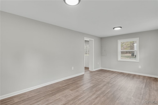 empty room with electric panel and light wood-type flooring