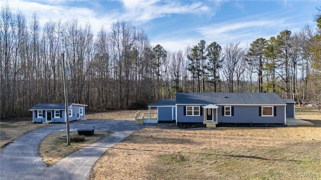 view of front of property featuring a carport, a front yard, and an outbuilding