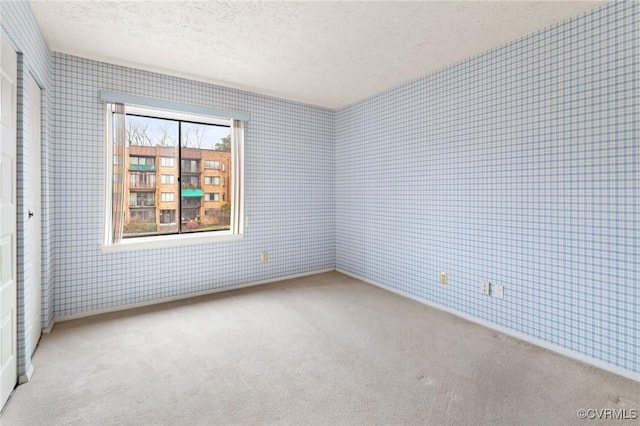 carpeted empty room featuring a textured ceiling