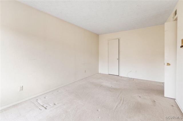 empty room with a textured ceiling and light colored carpet