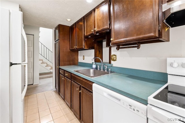 kitchen featuring sink, white appliances, dark brown cabinets, light tile patterned floors, and a textured ceiling