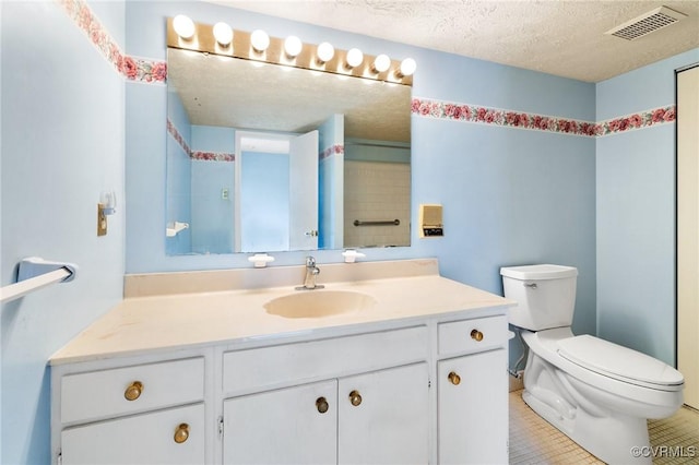 bathroom featuring toilet, vanity, a textured ceiling, and tile patterned floors