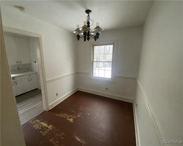 unfurnished dining area featuring a notable chandelier and dark hardwood / wood-style floors