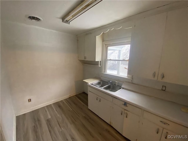 kitchen with hardwood / wood-style flooring, sink, and white cabinetry