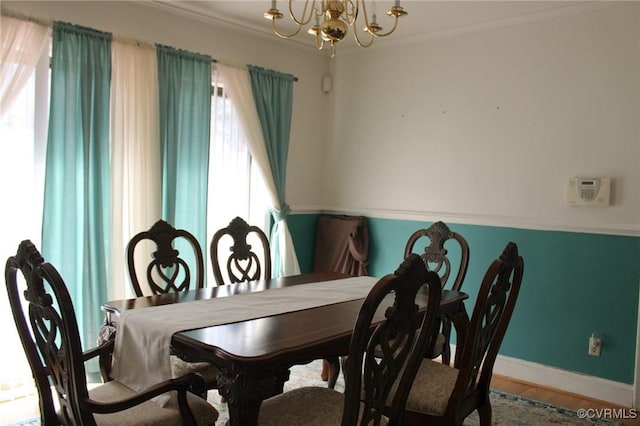 dining space featuring baseboards, crown molding, an inviting chandelier, and wood finished floors