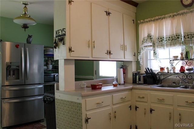 kitchen featuring white cabinetry, light countertops, stainless steel refrigerator with ice dispenser, and a sink