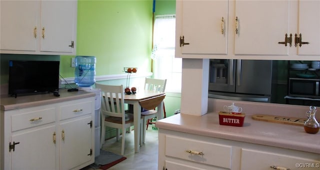 kitchen with light countertops, fridge with ice dispenser, and white cabinets