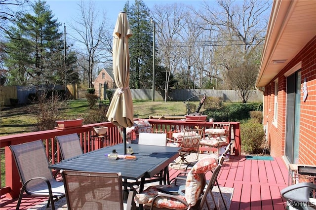 wooden deck featuring outdoor dining area, a lawn, and a fenced backyard