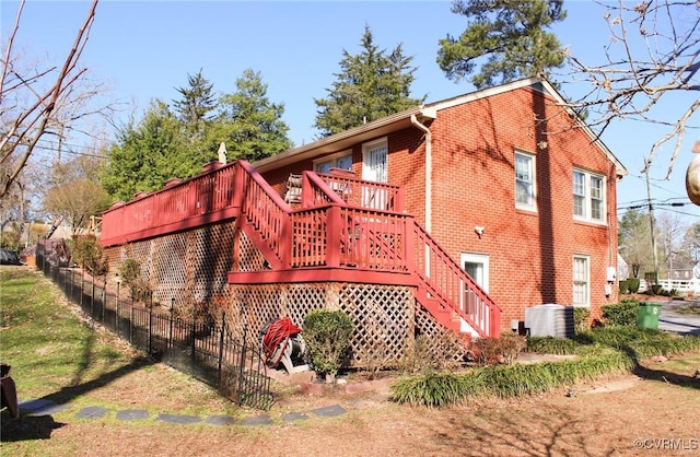 view of property exterior featuring fence, a wooden deck, central AC, stairs, and brick siding