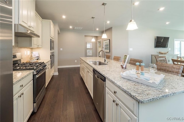 kitchen with stainless steel appliances, decorative light fixtures, a large island with sink, sink, and white cabinets