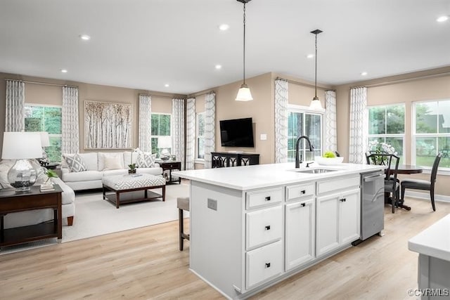 kitchen with a center island with sink, dishwasher, white cabinets, decorative light fixtures, and sink