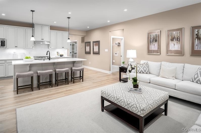 living room featuring sink and light hardwood / wood-style floors