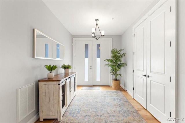 foyer with visible vents, baseboards, light wood-style floors, french doors, and an inviting chandelier