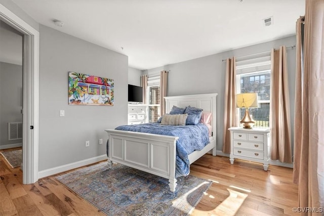 bedroom with light wood-type flooring, visible vents, and baseboards