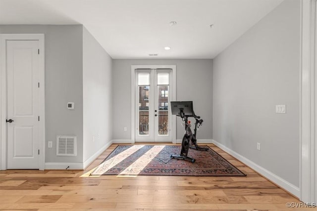 workout area with baseboards, french doors, visible vents, and light wood-style floors