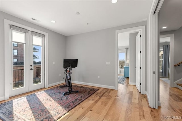 exercise area featuring light wood-type flooring, baseboards, visible vents, and french doors