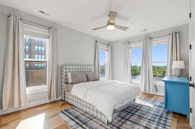 bedroom with baseboards, ceiling fan, visible vents, and light wood-style floors