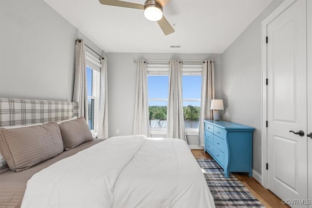 bedroom with baseboards, wood finished floors, visible vents, and a ceiling fan