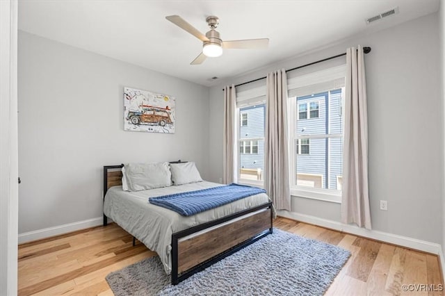 bedroom featuring a ceiling fan, light wood-type flooring, visible vents, and baseboards