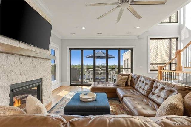 living room with stairs, crown molding, light wood-style floors, a fireplace, and recessed lighting