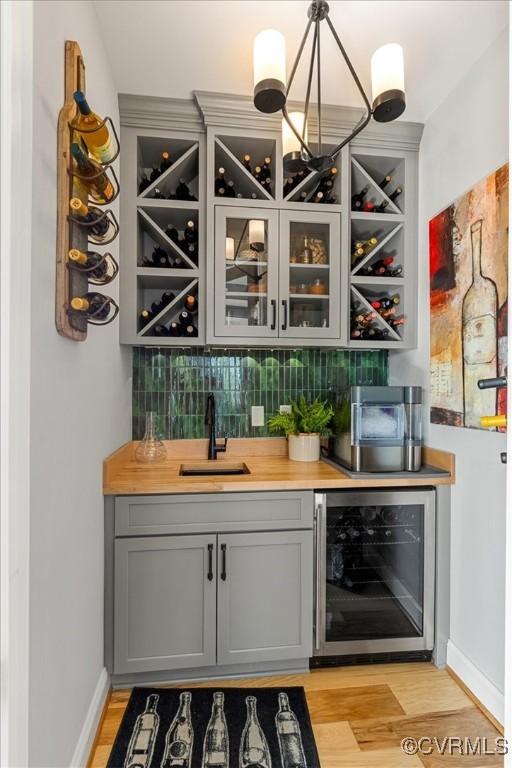 bar featuring wine cooler, indoor wet bar, a sink, and light wood-style floors