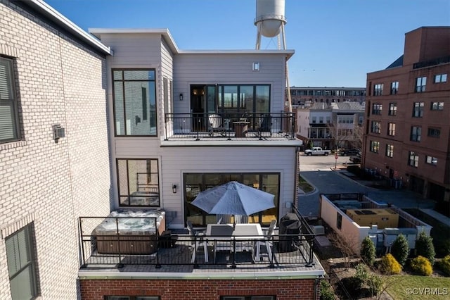 back of property featuring brick siding and a balcony