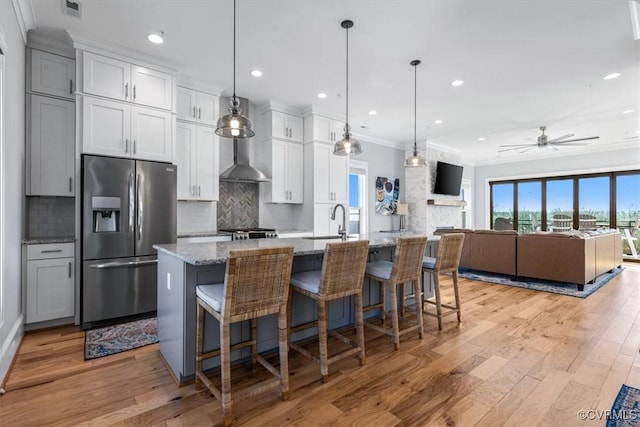 kitchen featuring light stone counters, pendant lighting, a large island, stainless steel refrigerator with ice dispenser, and open floor plan