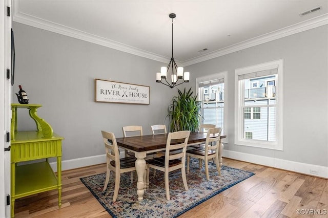 dining space featuring a notable chandelier, baseboards, crown molding, and wood finished floors