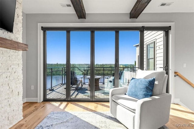 doorway to outside featuring beam ceiling, light wood-type flooring, and visible vents