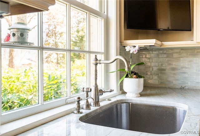 details with sink, tasteful backsplash, and light stone counters