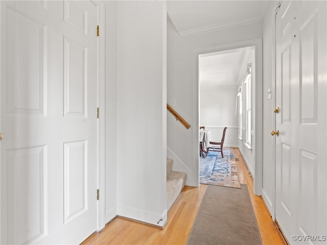 hall with ornamental molding and light hardwood / wood-style flooring