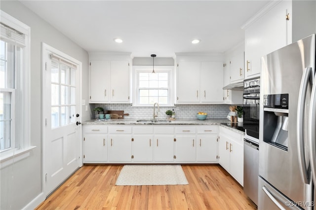 kitchen with white cabinets, appliances with stainless steel finishes, sink, and decorative light fixtures