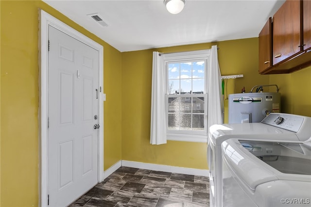 washroom with cabinets, water heater, and washer and clothes dryer