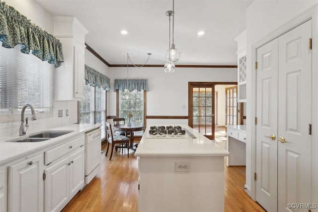 kitchen with white appliances, light countertops, decorative light fixtures, and white cabinetry