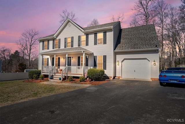 colonial house with a yard, a porch, and a garage