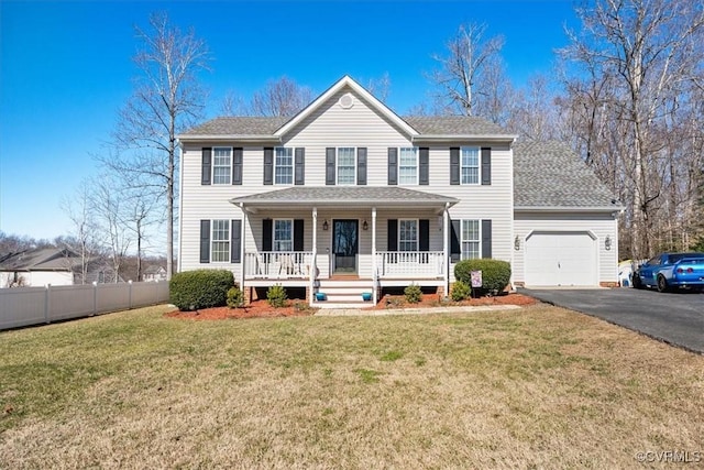 colonial house featuring a porch, a garage, and a front yard