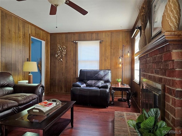 living room with wood walls, ornamental molding, dark wood-type flooring, and a brick fireplace