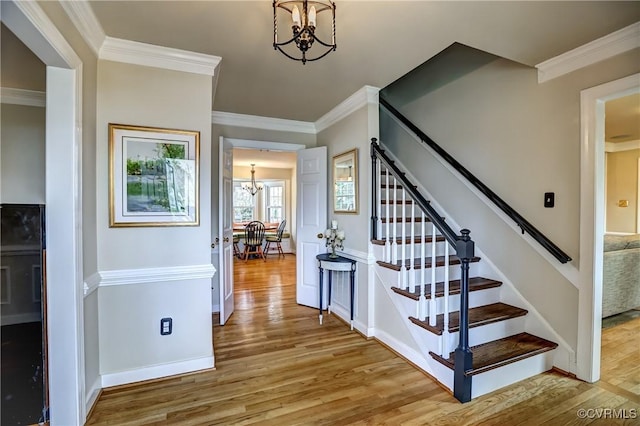 stairway featuring hardwood / wood-style flooring, crown molding, and an inviting chandelier