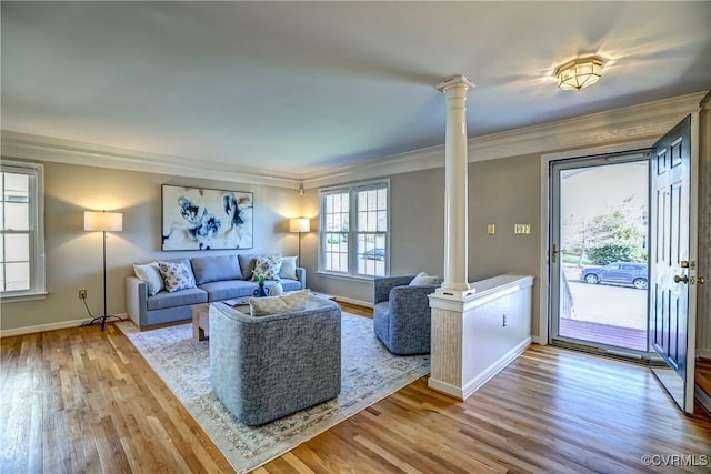 living area featuring ornamental molding, decorative columns, baseboards, and wood finished floors