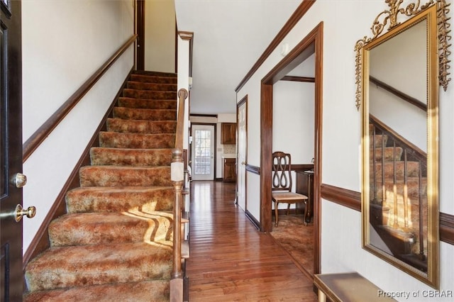 staircase featuring crown molding and hardwood / wood-style floors