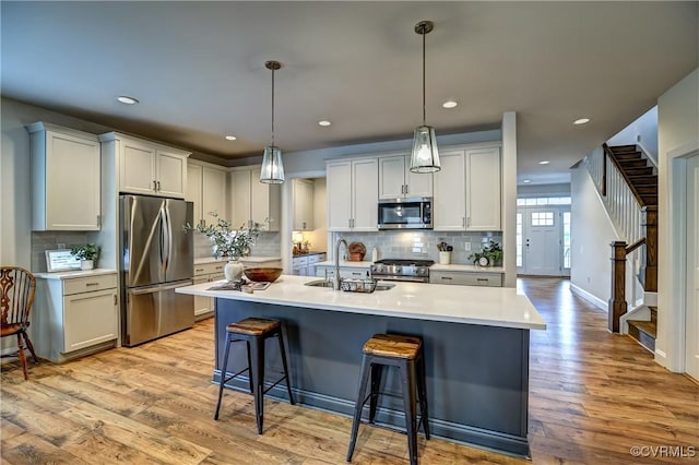 kitchen featuring white cabinets, hanging light fixtures, stainless steel appliances, and sink