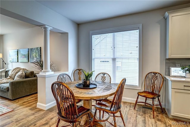 dining space with light wood-type flooring, ornate columns, and plenty of natural light